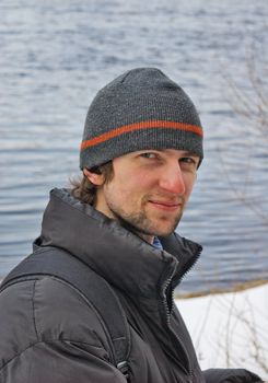 confident looking young man on winter river coast