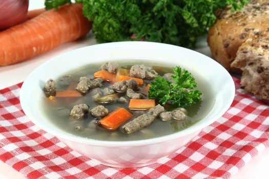 a bowl of soup with liver dumplings carrots and parsley