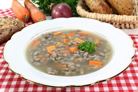 a plate of soup with liver dumplings carrots and parsley