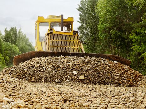 The bulldozer rakes up gravel for road alignment