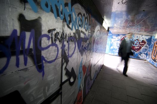 A man walk in a tunnel with graffiti