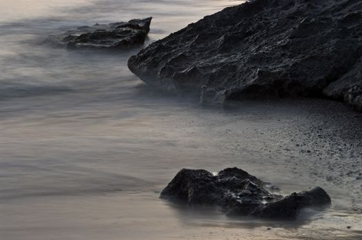 Seashore - closeup of rocks, waves and sand.