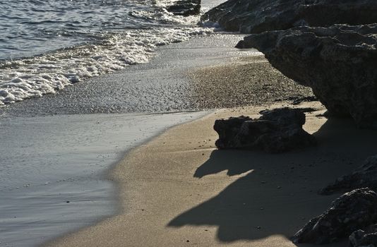 Seashore - closeup of rocks, waves and sand.