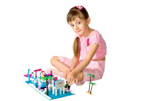 The little girl smiles and playing with the meccano
