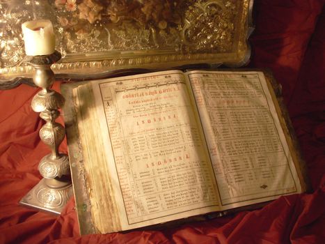 very old Bible, candlestick and icons on a Red shining silk background