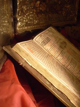 very old Bible and icon on a red shining silk background