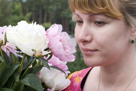 Beautiful young woman holding pink peony
