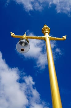 a gold-colored lamp post standing in the blue sky