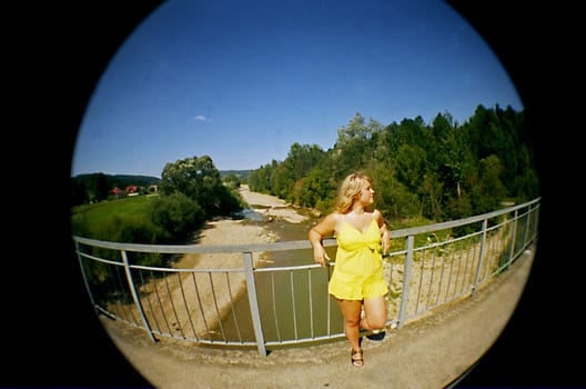 blonde girl on bridge over brook