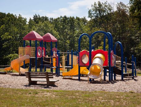 Modern playground for children in leafy park with slides and climbing frames