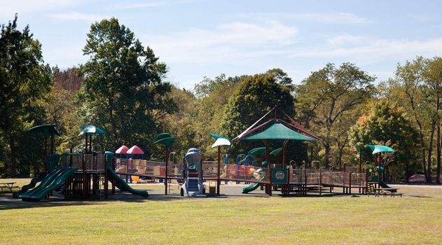 Modern playground for children in leafy park with slides and climbing frames