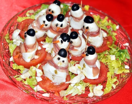 Traditional Italian spiedini dish with tomato, mozzarella cheese, olives and ham with lettuce salad