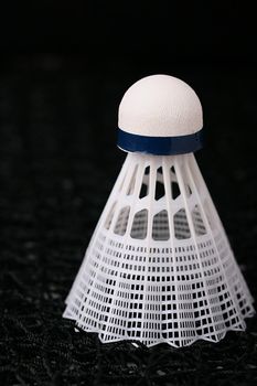 Close-up of a white synthetic shuttlecock on a badminton net.