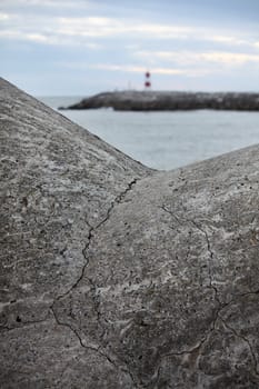 View of a breakwater on the pier and a lighthouse on the back.