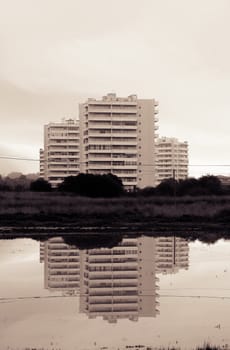 Three tall buildings creating a reflection mirror on the water.