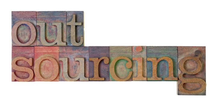 outsourcing word in vintage wood letterpress type blocks, stained by color ink, isolated on white