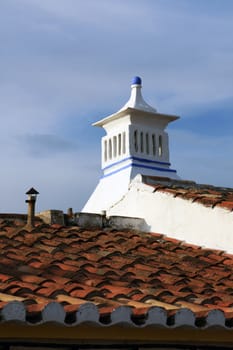 View of a typical portuguese rooftop with white chimney and orange tiles.