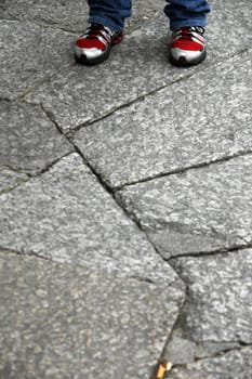 View of the red tennis on the upper part of the photo on a gray pavement.