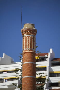 View of an old brick factory chimney on a urban surrounding.