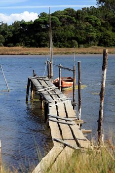 View of a old and fragile wooden pier with a small fishing boat.