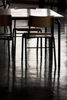 View of some school chairs and a table on a dark room.