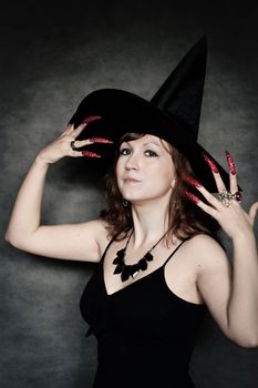 Pretty young witch with black hat and long nails