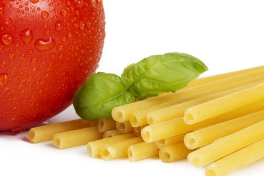 raw macaroni with tomato and basil closeup on white background