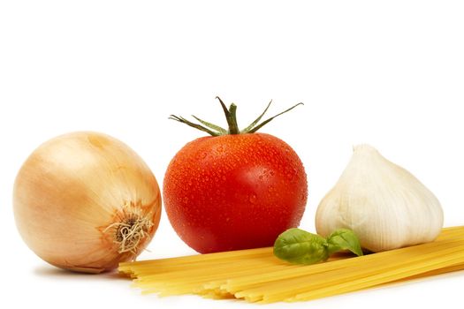 raw spaghetti with tomato, basil, garlic and onion on white background