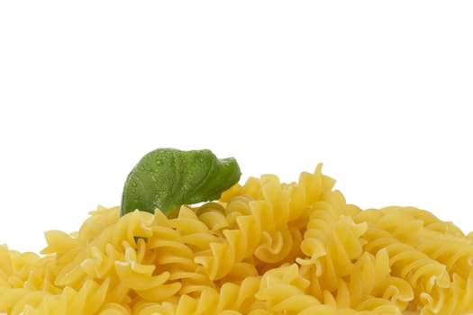 some raw fusilli with wet basil on white background