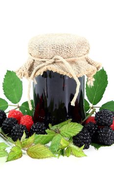 a glass of berry jam and fresh fruit on a white background