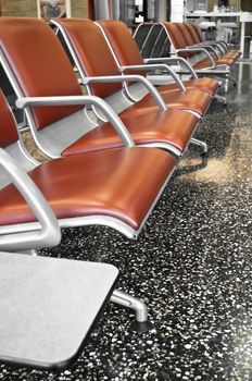 Brown and steel airport seats before gating in waiting room