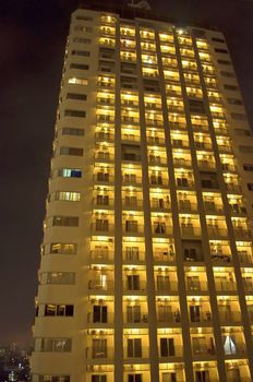 Tall skyscraper apartments by night on yellow light