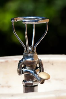 Close up view of a drinkable public water fountain on a park.