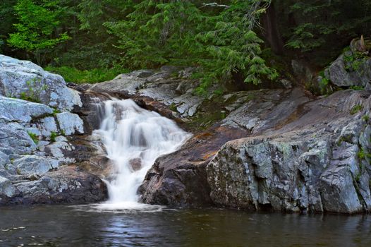 A waterfall surrounded by rocks and trees.