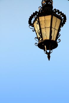 Close up view of a vintage street lamp over a blue sky.