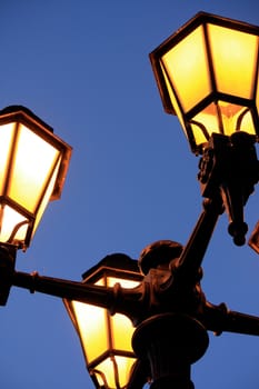 View of a vintage four arm piece streetlight lit on the approach of the night.