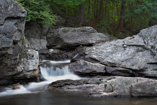 A small waterfall over rock with a forest in the background