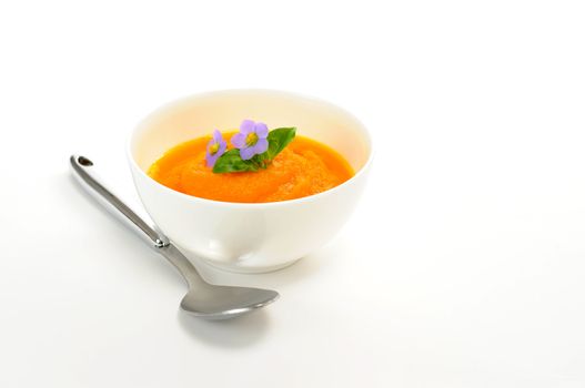 Delicious homemade carrot soup with edible flower garnish.