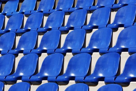 View of many aligned blue plastic seats on a stadium.
