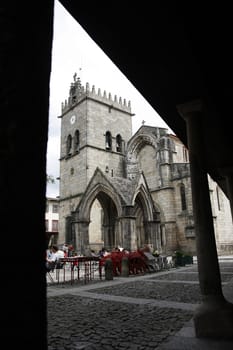 Square of the old historical area of Guimaraes city on Portugal, featuring the church Nossa Senhora de Oliveira and some tourists.