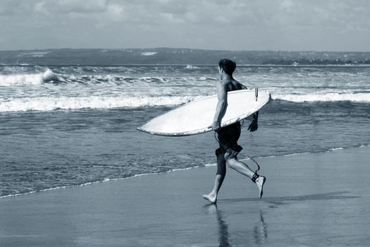 Man-surfer with board on a coastline. Bali. Indonesia