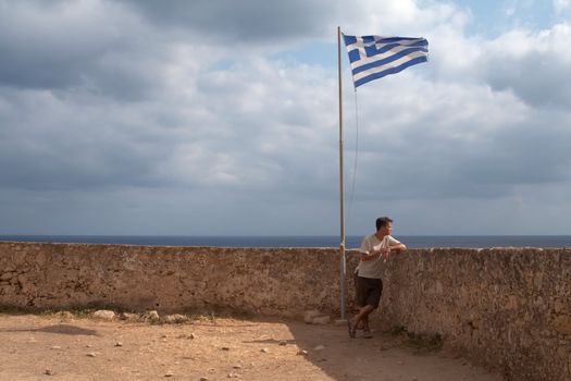 young man staying near the stone wall  on a marine panorama