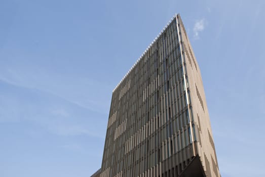 A Triangular Cream and Brown Office Block under a blue sky