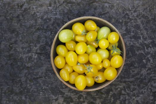 A bowl of yellow pear shaped tomatoes in a white china bowl shot from above.