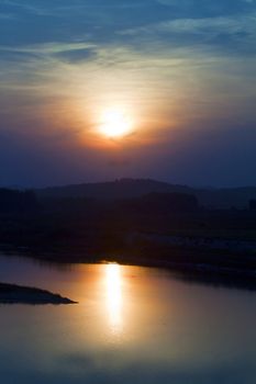 Beautiful orange sunset over the river, with black silhouettes of trees