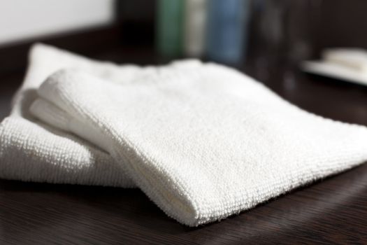 Two white wash cloths on dark wood countertop