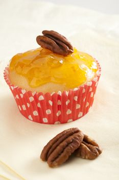 Yellow cupcake topped with pecans and jam.