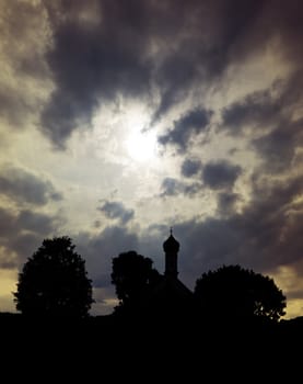 An image of a dramatic sky with church in bavaria germany