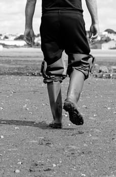 Fisherman walking on the mud, with some long boots.