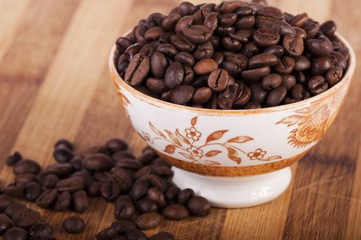 Close view of a bunch of roasted beans of coffee inside a bowl.